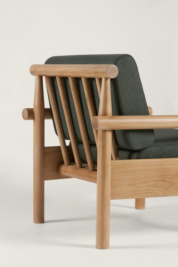 a wooden chair with a green seat and back cushion on the side, in front of a white background