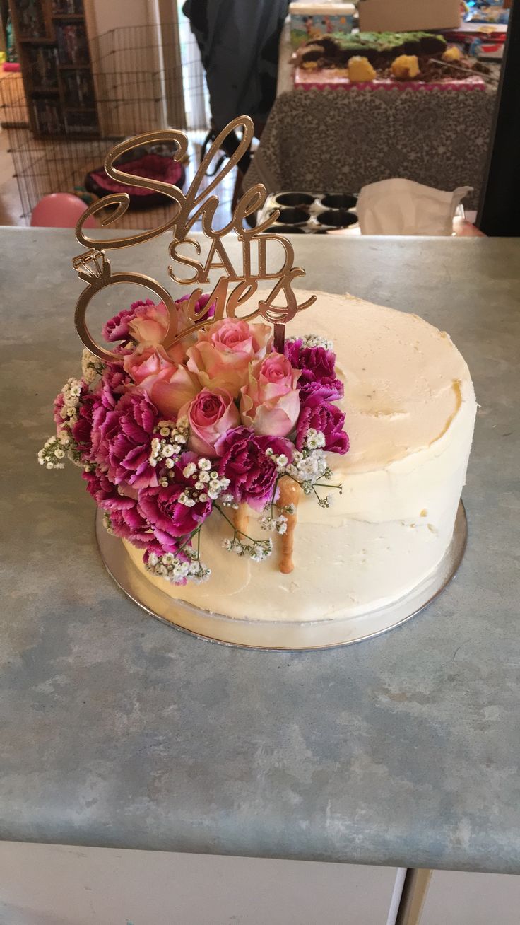 a white cake with pink flowers and the word sale spelled out in gold on top