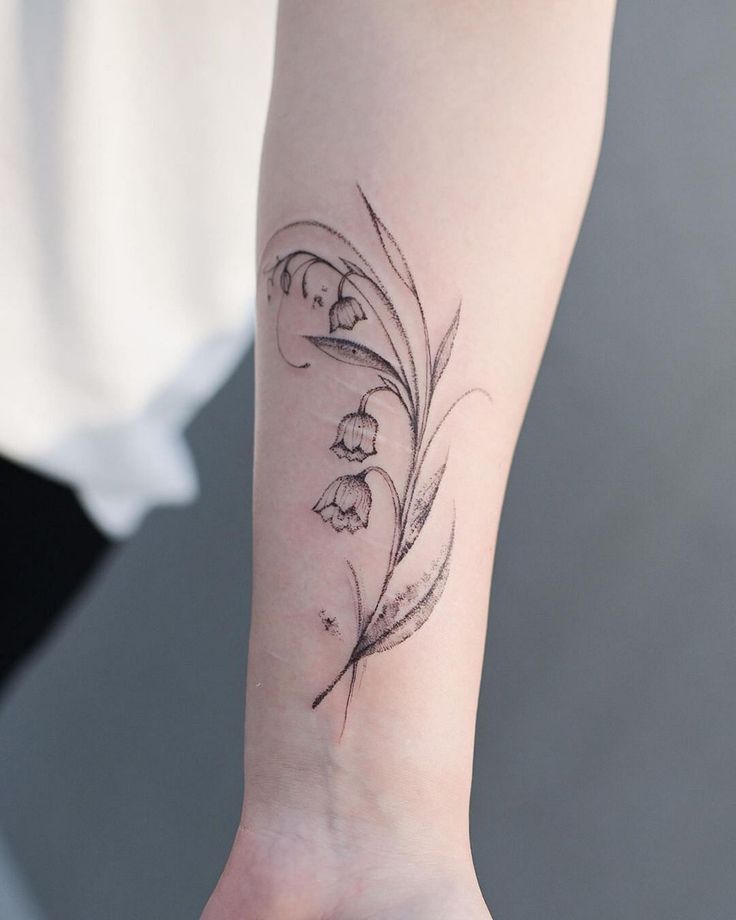 a woman's arm with a flower tattoo on the left side of her wrist