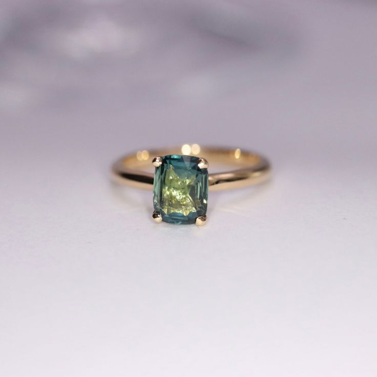 a ring with a green stone in it on a white surface, close - up