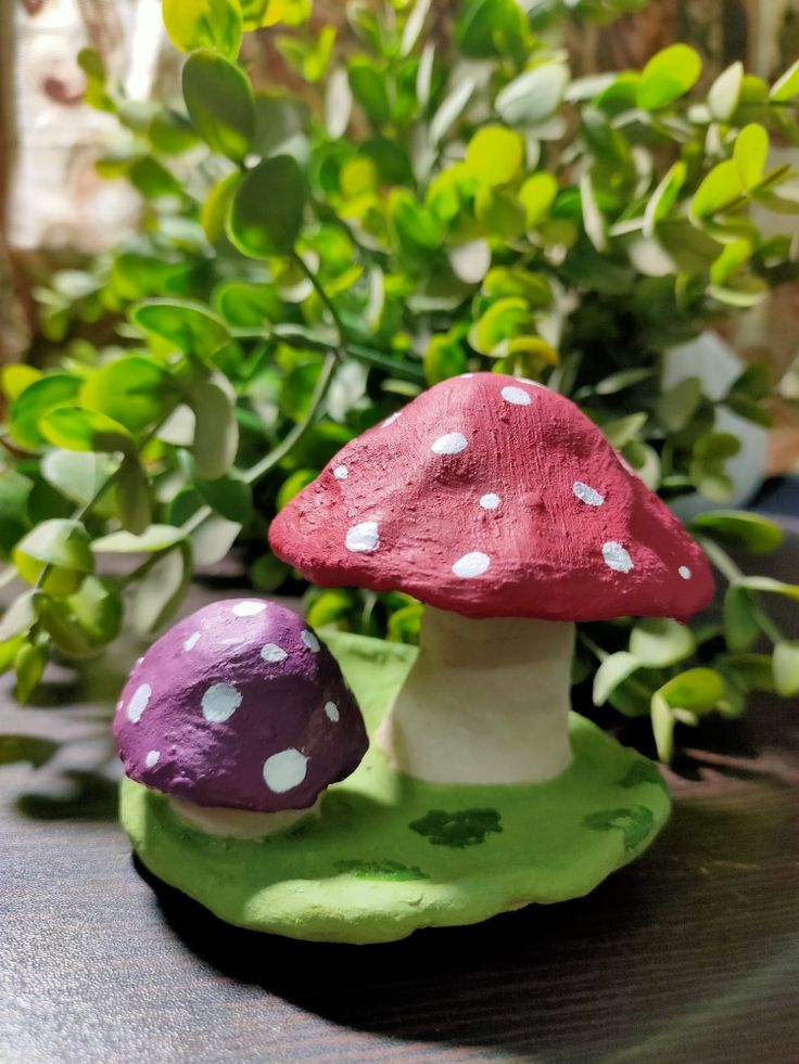 two small mushrooms sitting on top of a green plate next to a bush and potted plant