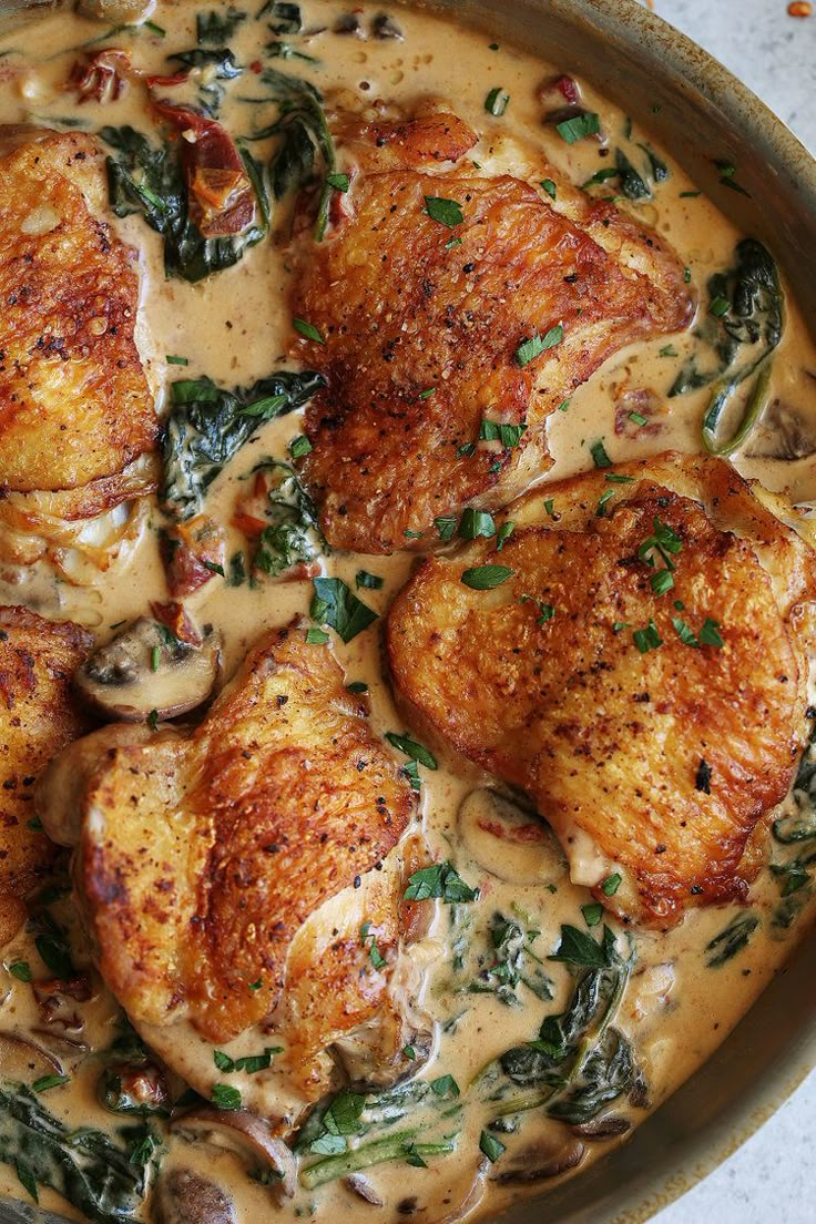 some chicken is covered in gravy and garnished with spinach