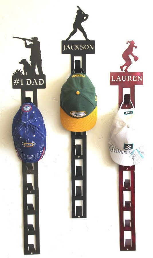 three hats are hanging on the wall and one is holding a hat rack with baseball caps