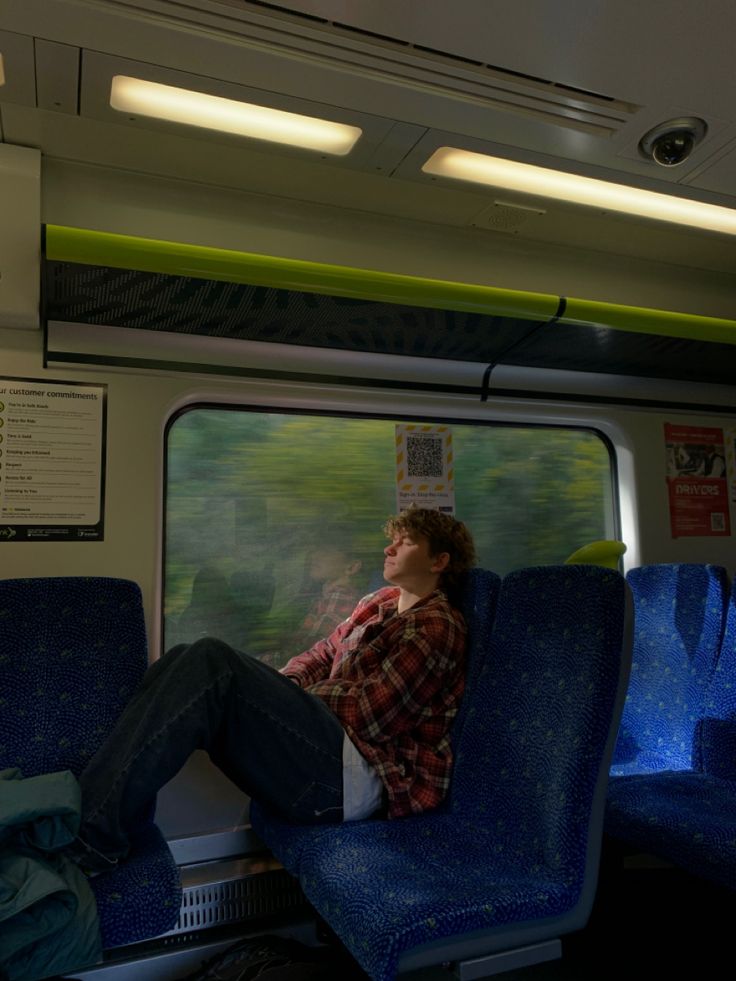 a man sitting on a train seat with his head resting on the back of it