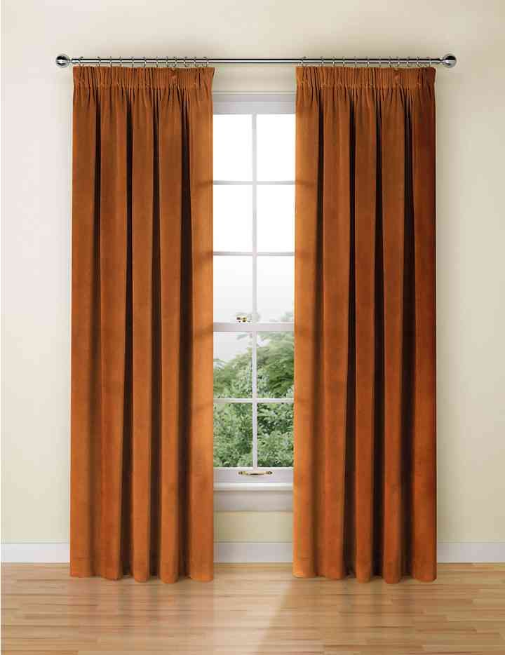 an orange curtain hanging in front of a window with wood flooring and white walls