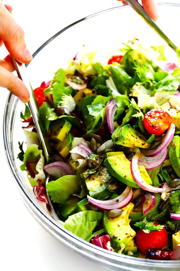 someone is cutting into a salad in a glass bowl