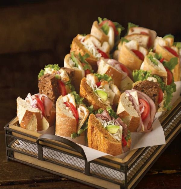 a tray filled with sandwiches on top of a wooden table