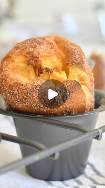 two doughnuts sitting in a metal pan on a white and black tablecloth