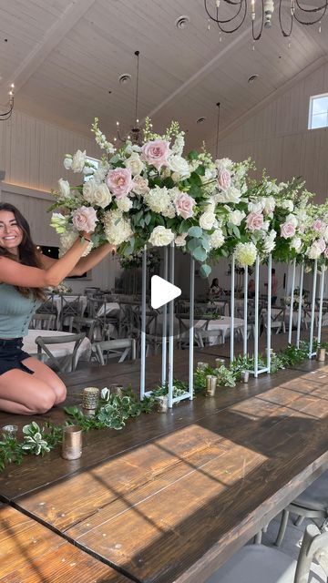 a woman kneeling down next to a table with flowers on it