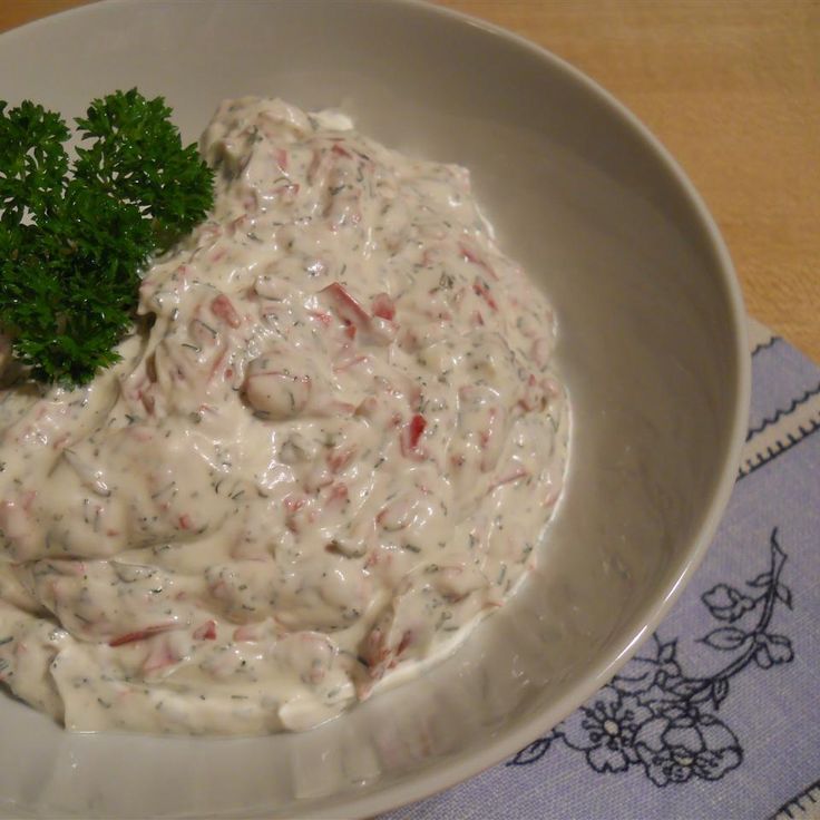 a white bowl filled with food on top of a wooden table next to a napkin