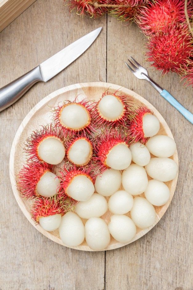 a wooden plate topped with fruit next to a knife and fork