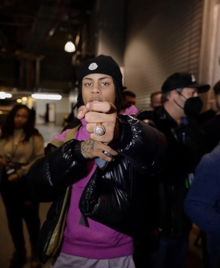 a man with a ring on his finger pointing at the camera while standing in front of other people