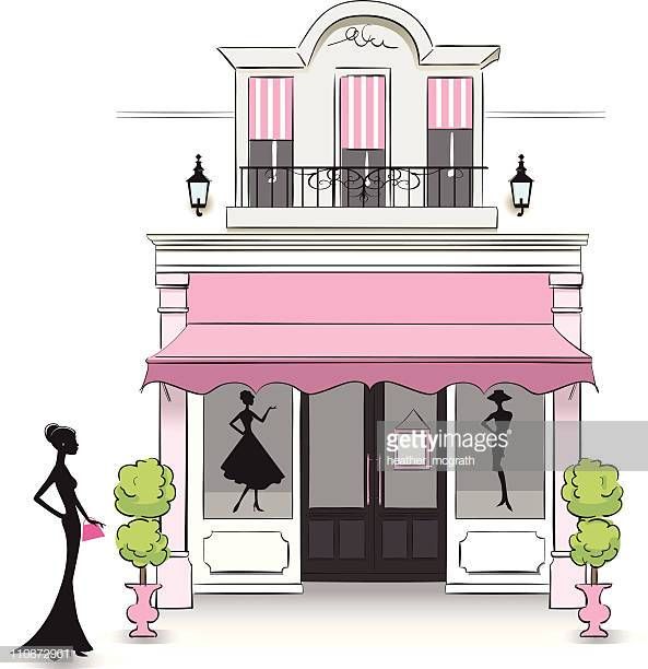 a woman standing in front of a pink storefront with mannequins on it