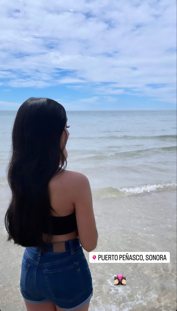 a woman standing on top of a beach next to the ocean