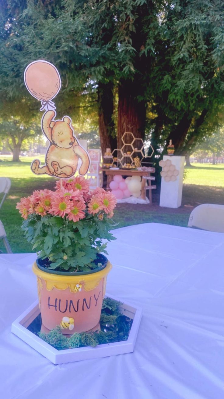 a winnie the pooh potted plant on top of a table with flowers in it