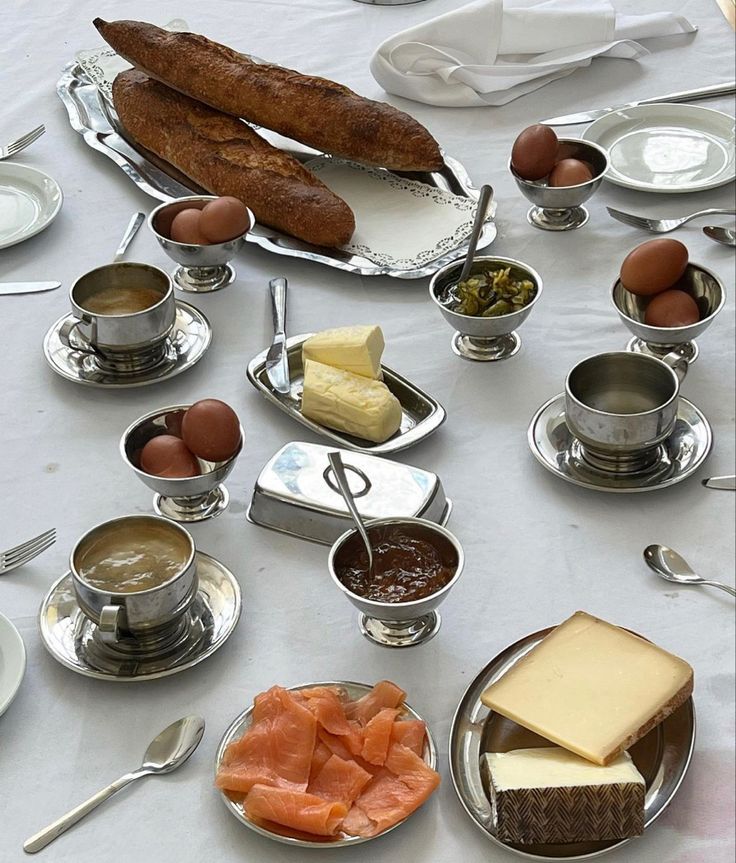 a table topped with lots of different types of food and silver dishes filled with meats