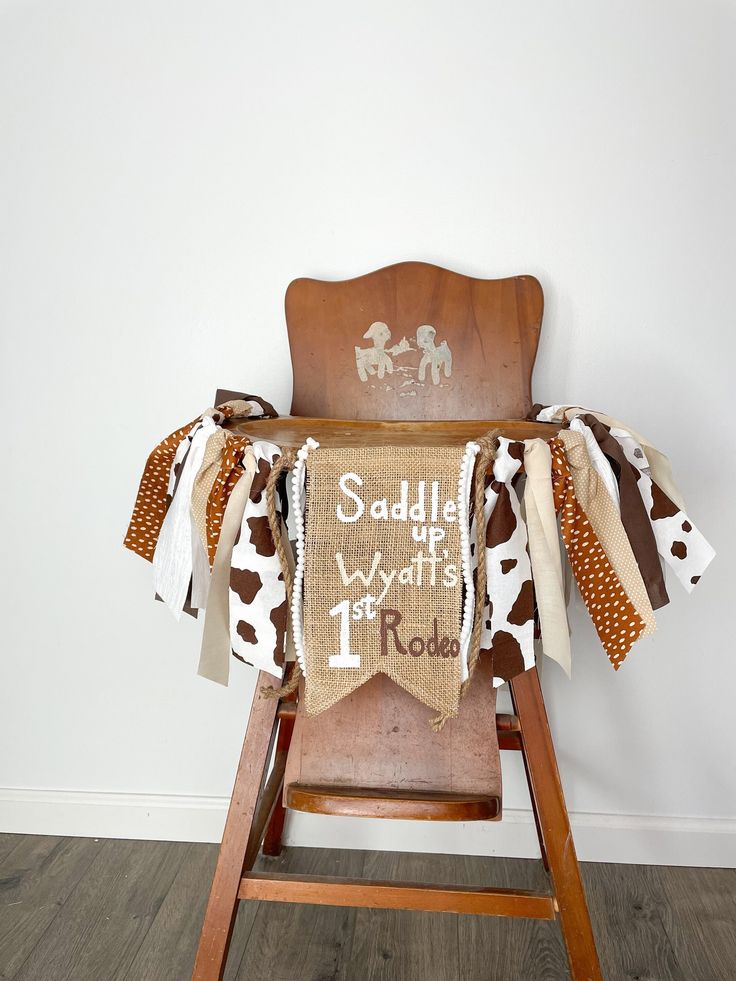 a baby's rocking chair with a personalized sign on the back and cow print fabric