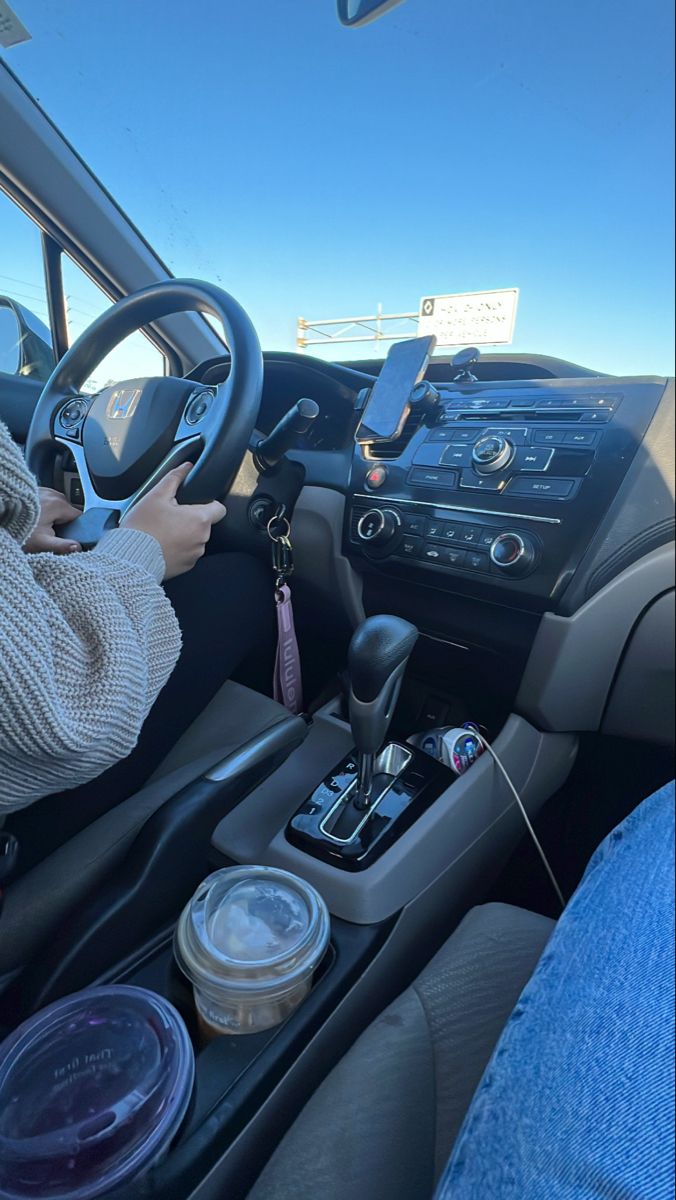 a person sitting in the driver's seat of a car holding a cell phone