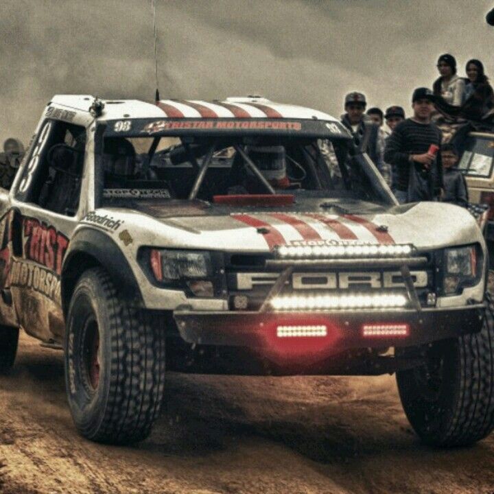 a group of people standing on top of a truck in the dirt