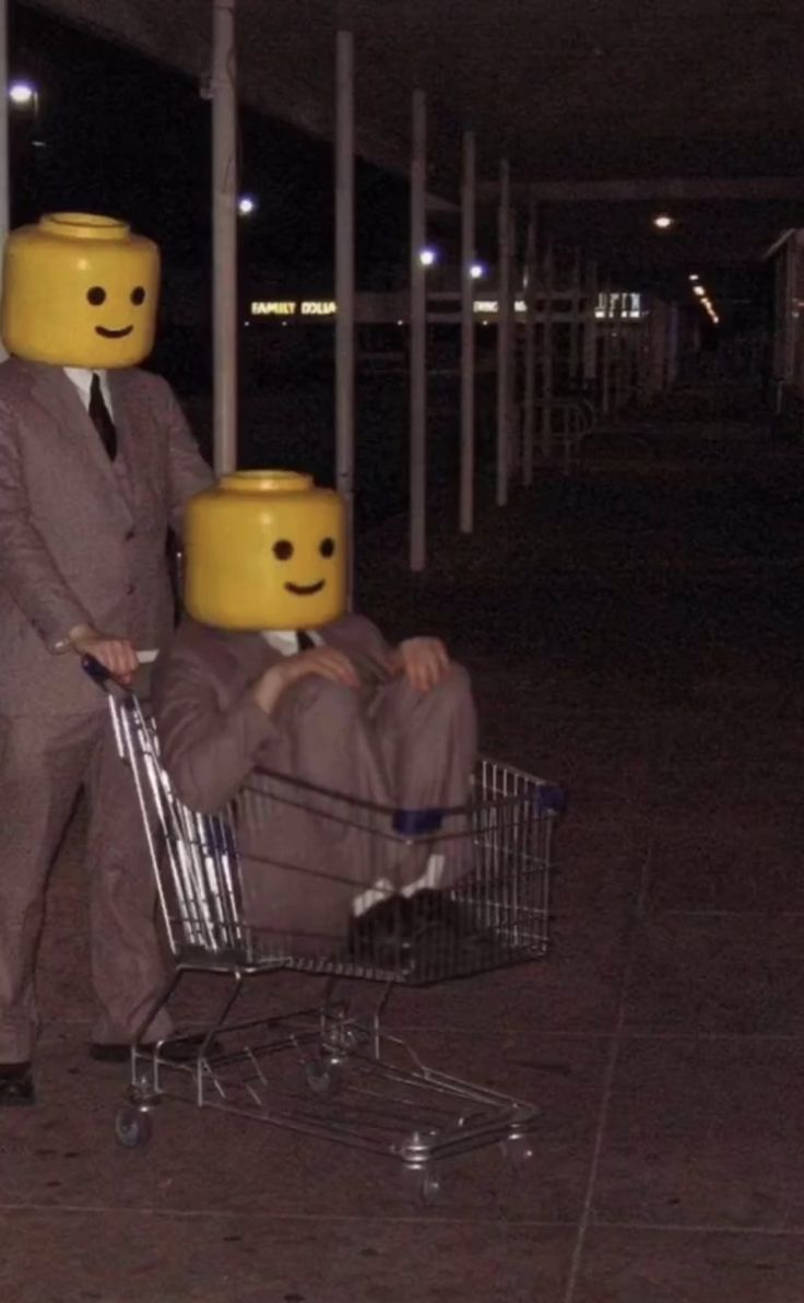 a man in a suit pushing a shopping cart with two legos on his head