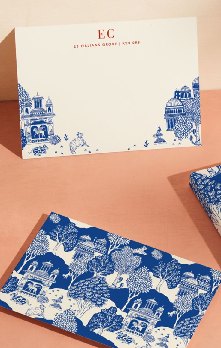 two blue and white greeting cards sitting next to each other on top of a table