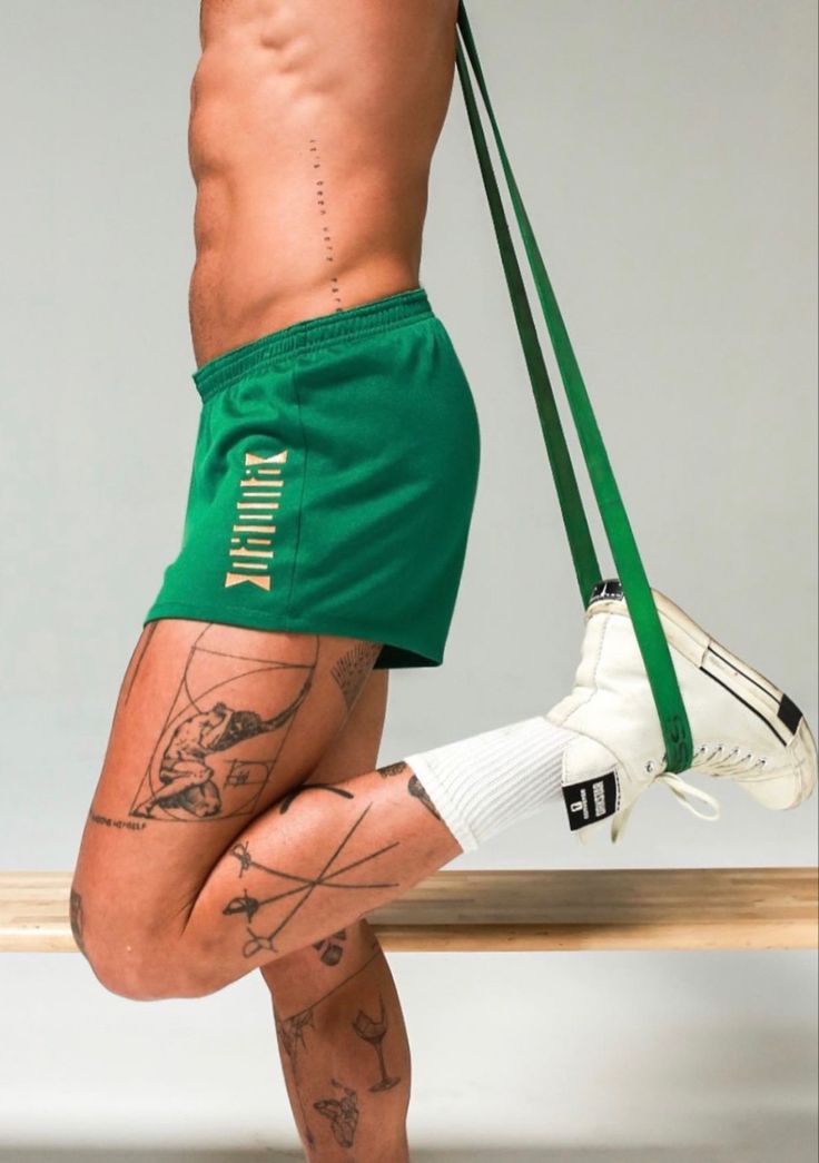 a man in green shorts and white socks with tattoos on his legs