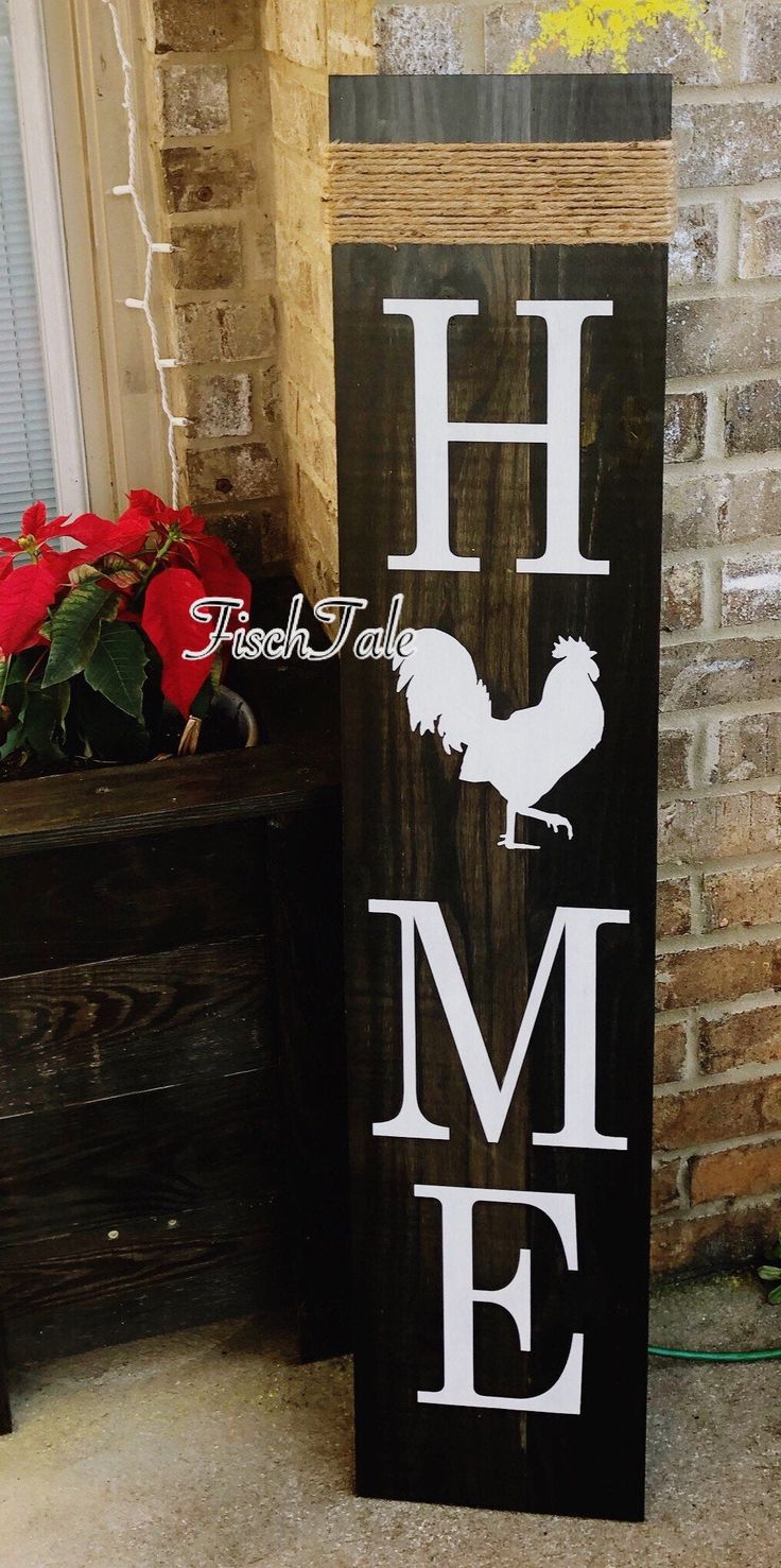 a wooden sign with the word home painted on it and rooster silhouettes in white