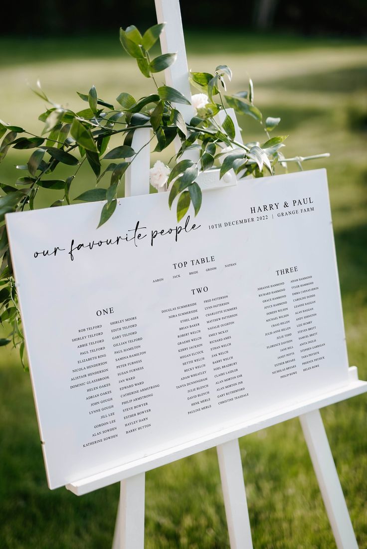 a white sign with greenery on it that says over four people and two tables