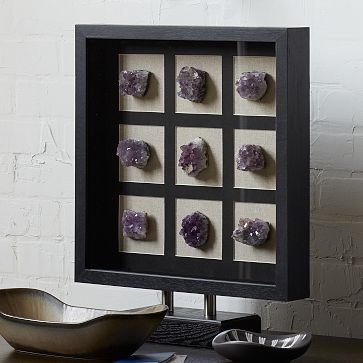 some rocks are in a shadow box on a table next to a bowl and spoon