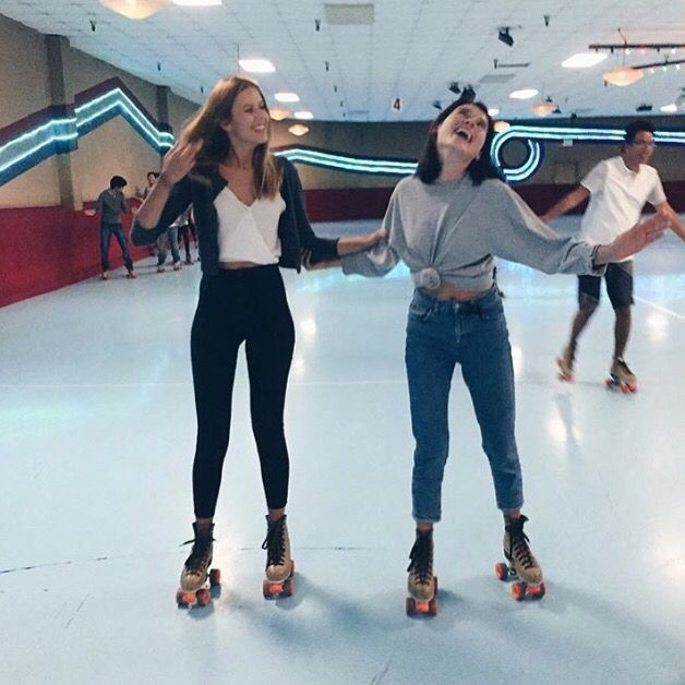 two girls are rollerblading in an indoor skating rink