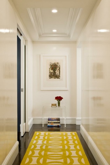 a yellow rug is in the middle of a hallway with white walls and black doors