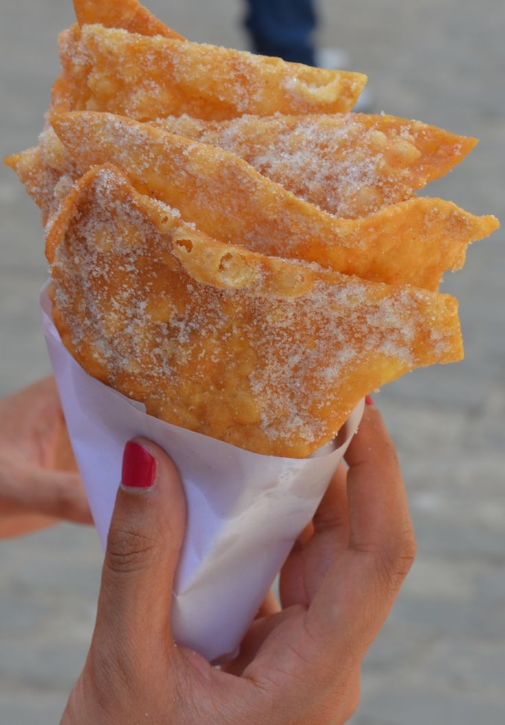 a person holding up a pastry with sugar on it's edges in front of the camera