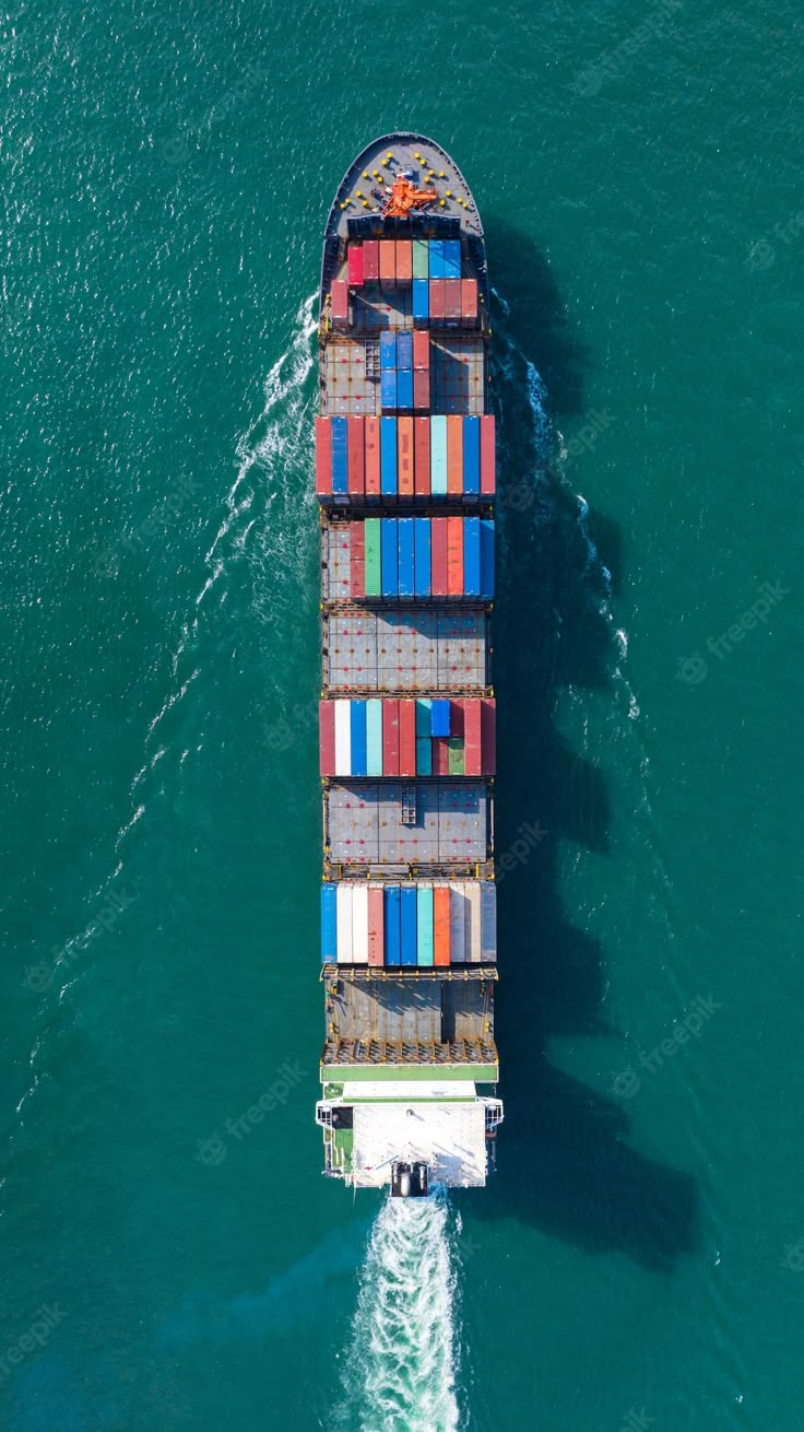 an aerial view of a container ship in the ocean with blue water and green background