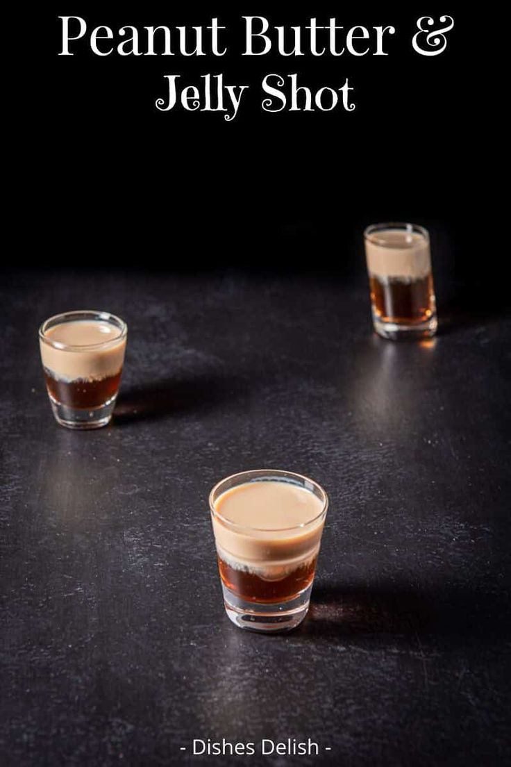 two shot glasses filled with peanut butter and jelly shot on a black countertop next to each other