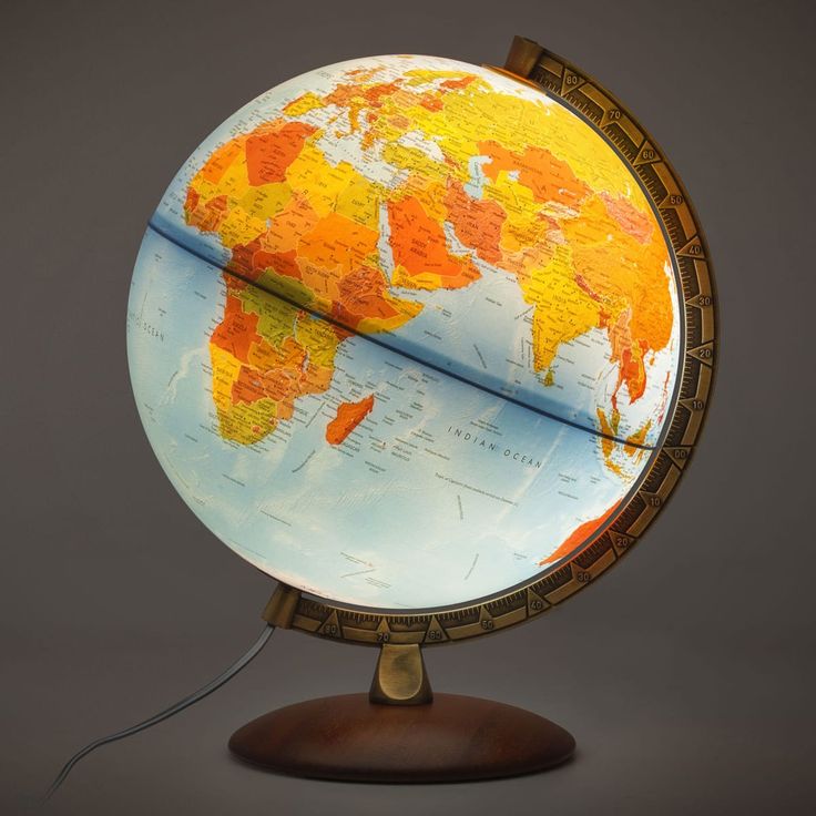 an illuminated globe on a wooden stand with a gray background and grey backdrop, showing the world