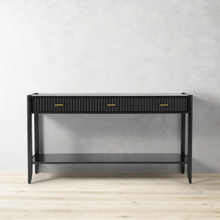 a black console table against a white wall with two gold handles on the top and bottom