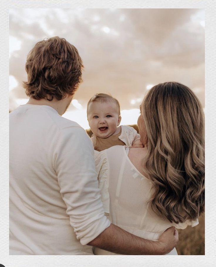 a man and woman holding a baby in their arms