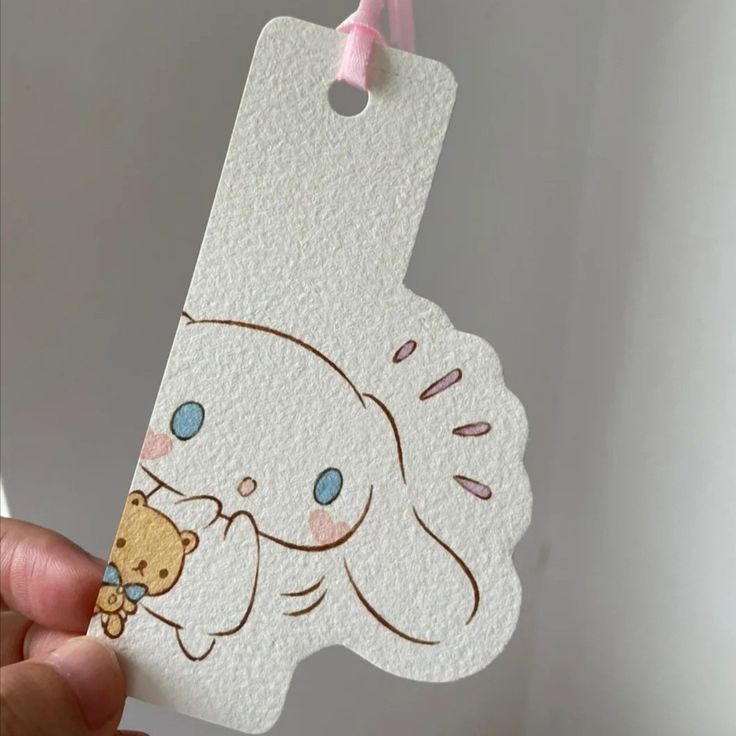 a person holding up a white tag with a bear on it