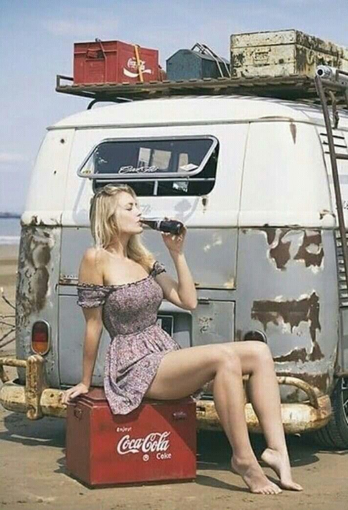 a woman sitting on top of a suitcase next to an old van