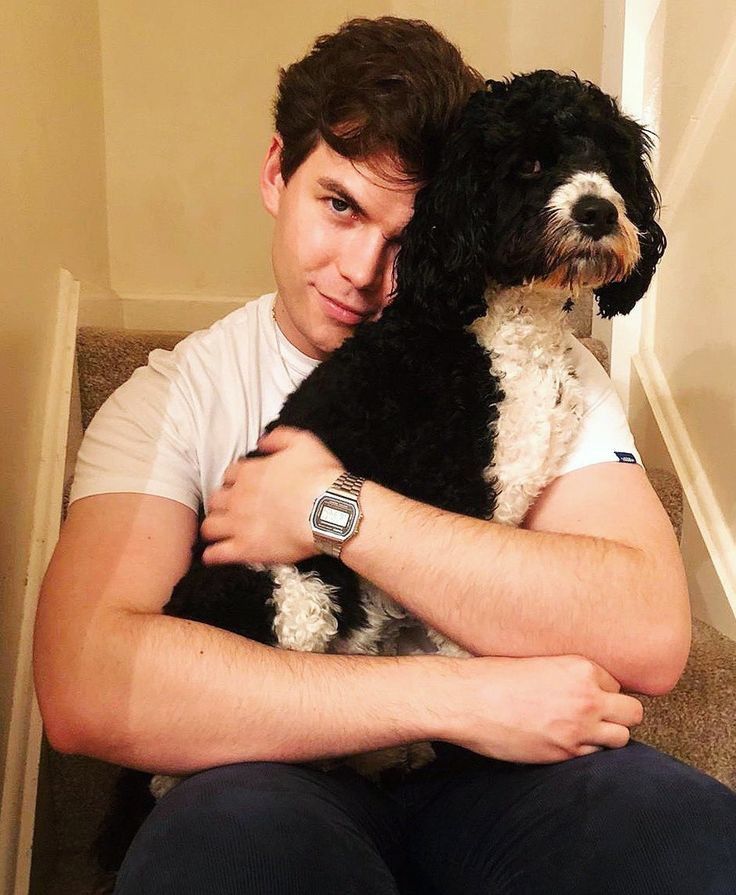 a man sitting on the stairs with his dog in his lap and looking at the camera