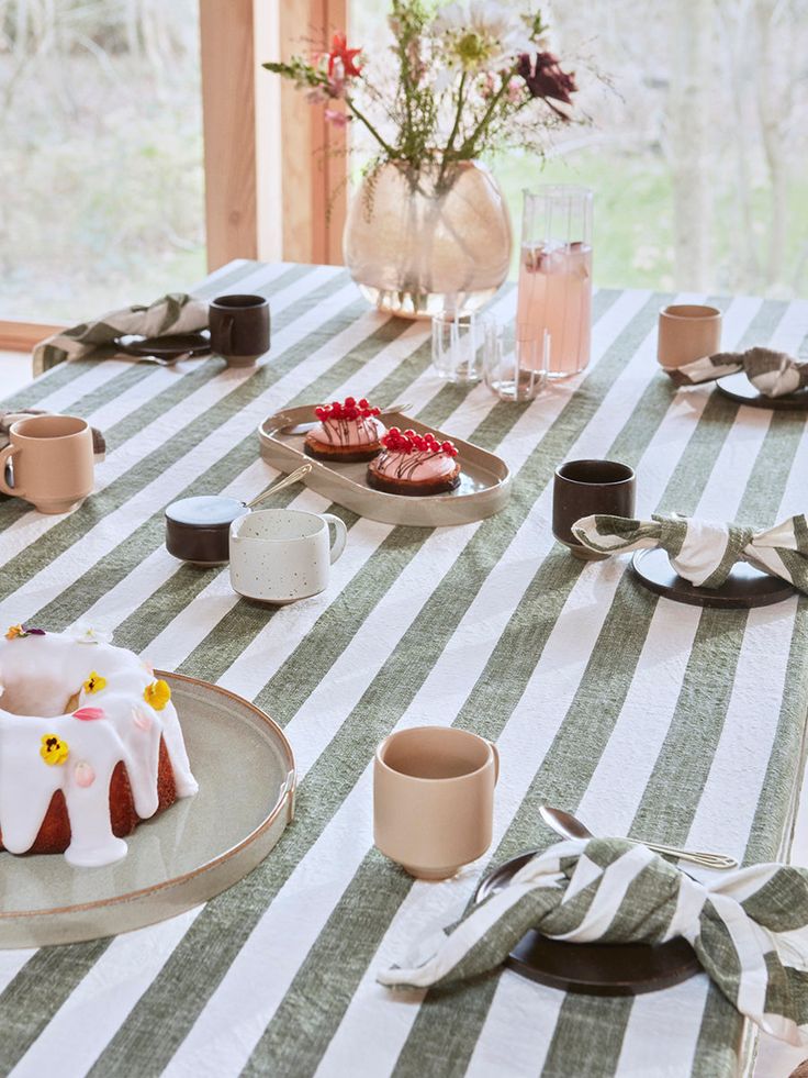 a table topped with plates and desserts covered in white frosting next to windows