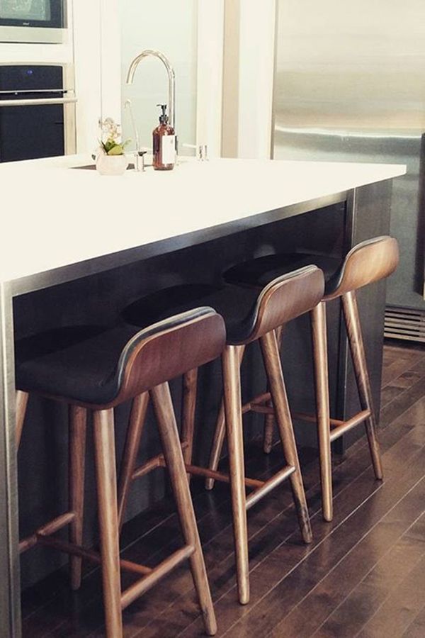 three bar stools sit at the center of a kitchen island in front of an oven