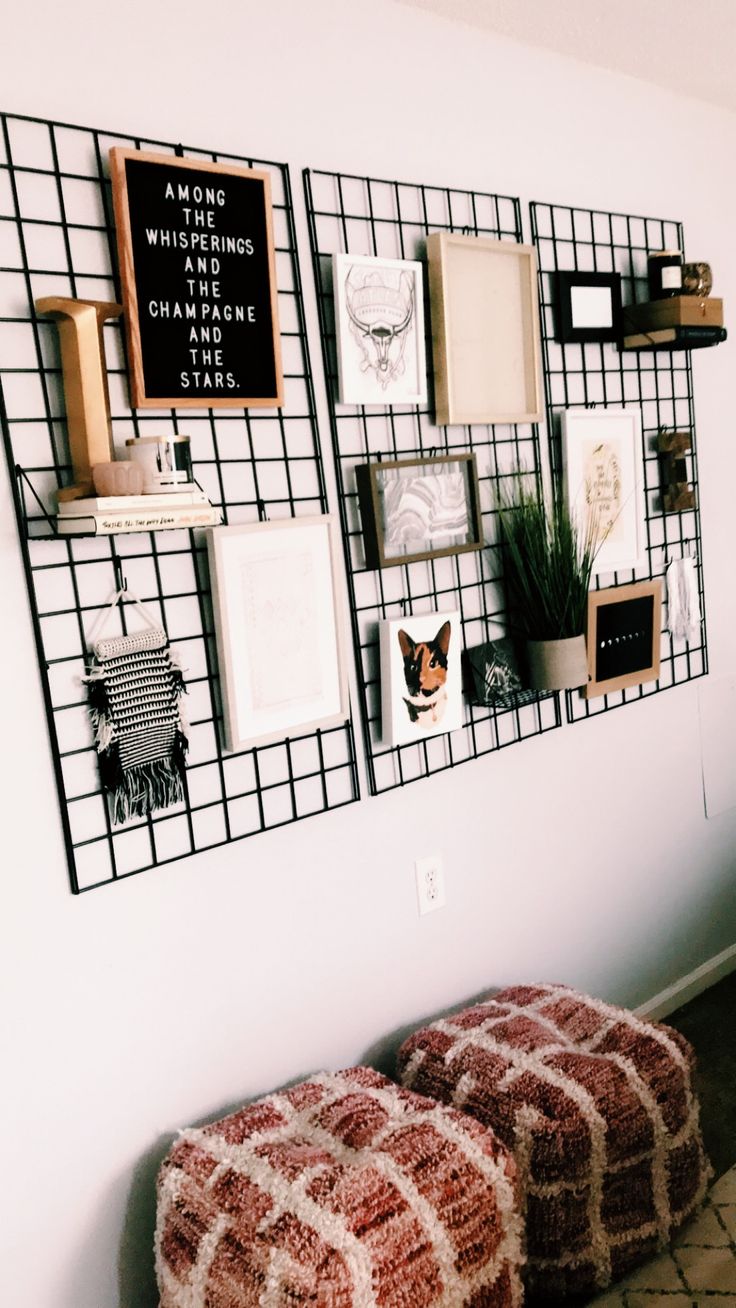 two poufles are sitting on the floor in front of a wall with pictures