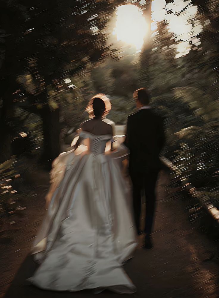 a bride and groom walking down a path in the woods at sunset or sunrise time