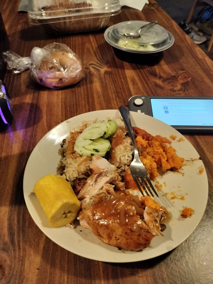 a white plate topped with meat and veggies next to a cell phone on a wooden table