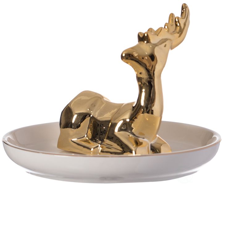 a gold reindeer figurine sitting on top of a white plate in front of a white background