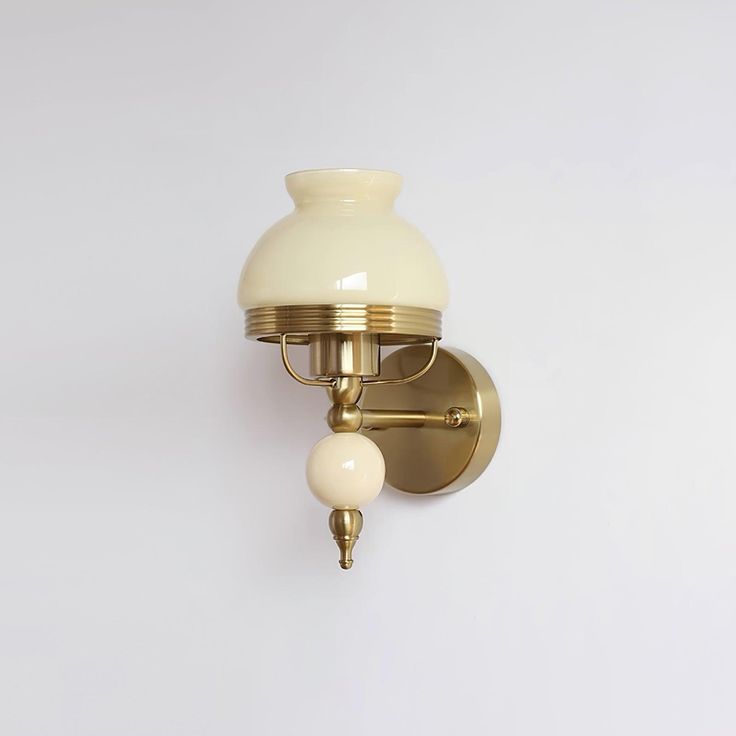 a wall mounted light with two white balls on it's arm and an attached bulb