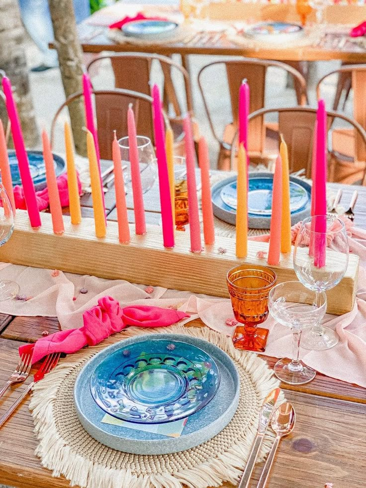 the table is set with colorful candles and place settings for an outdoor dinner or party