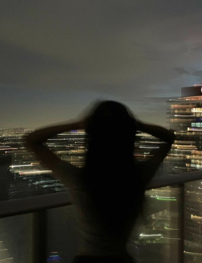 a woman standing on top of a tall building next to a night sky line with buildings in the background