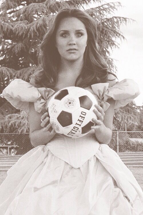 a woman in a dress holding a soccer ball